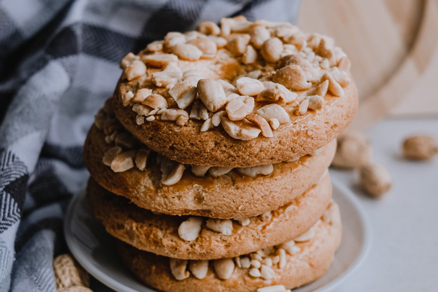 Four peanut cookies stacked on a small plate.