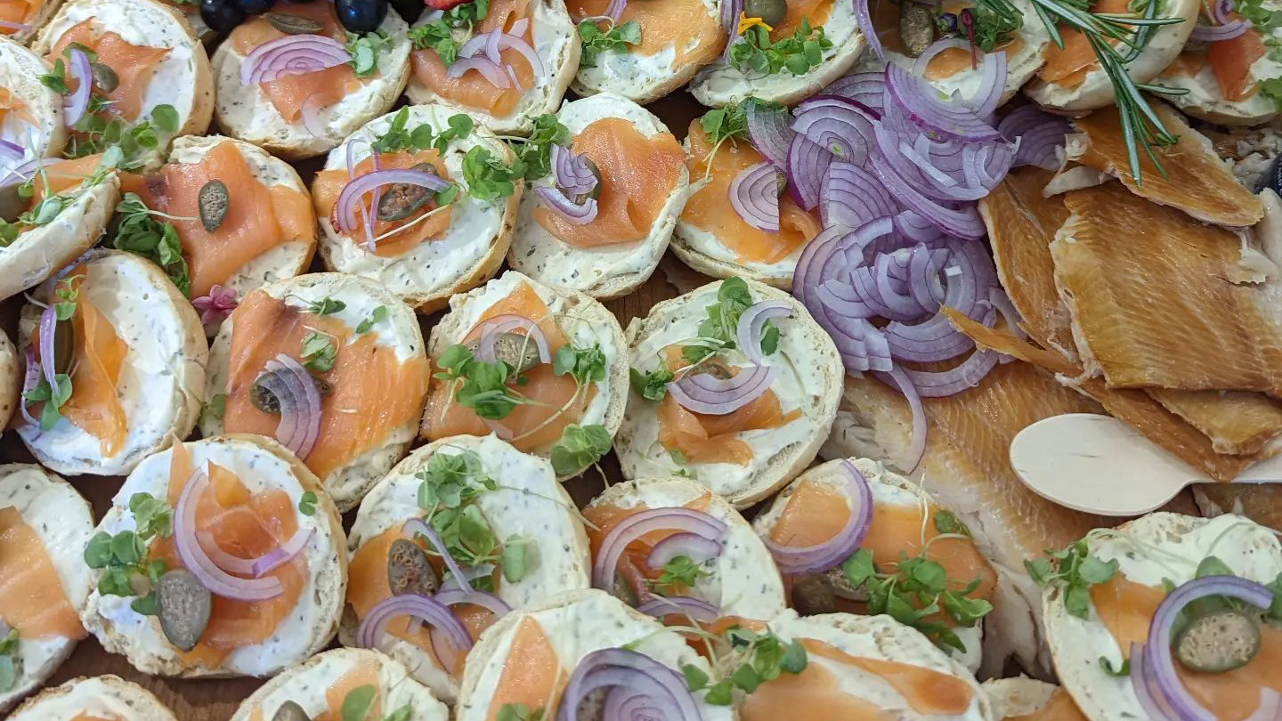 Catering spread of bagels with lox, red onion, and fresh microgreens.
